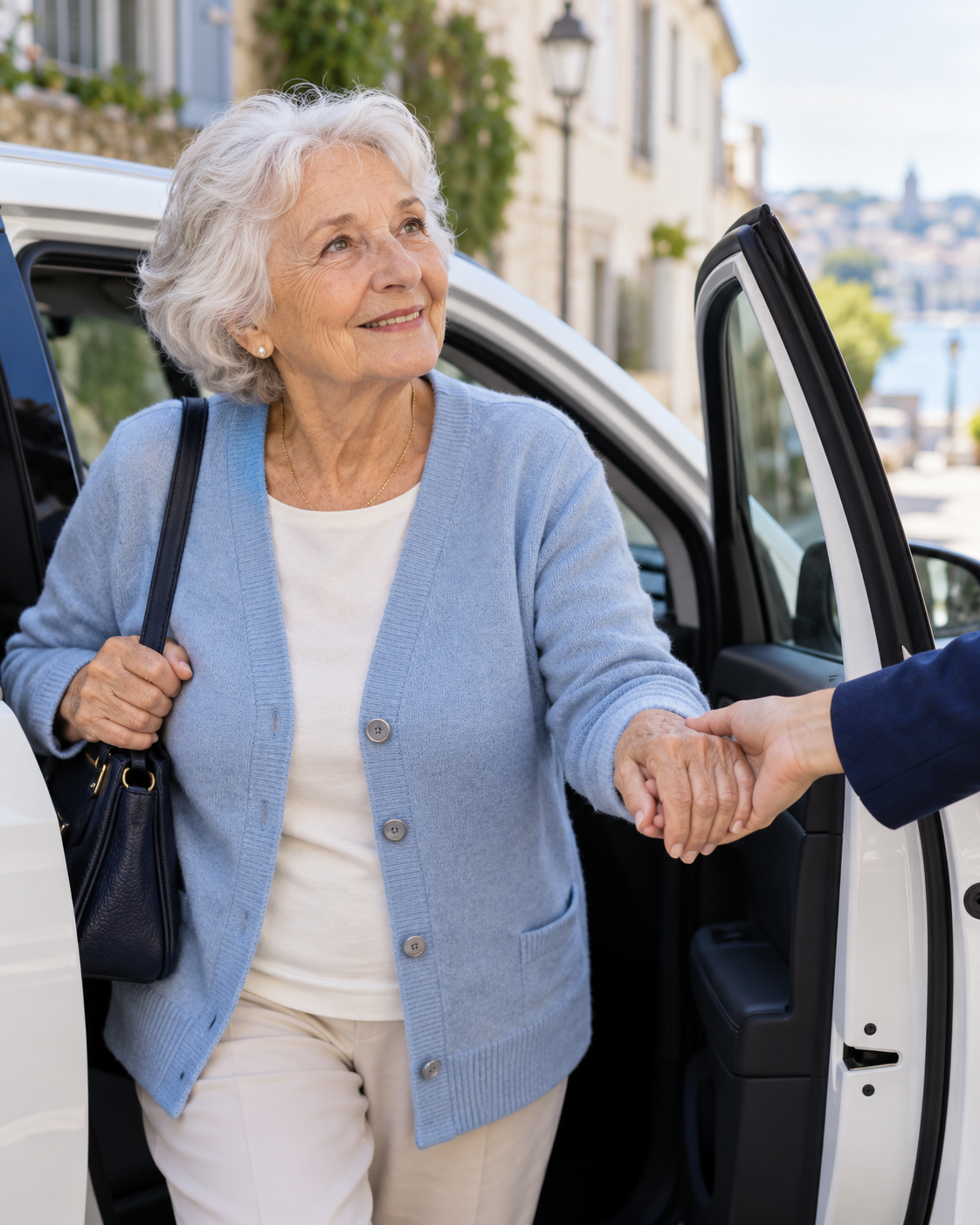 Une personne âgée prend la main tendue de la conductrice pour être accompagnée près d’une voiture